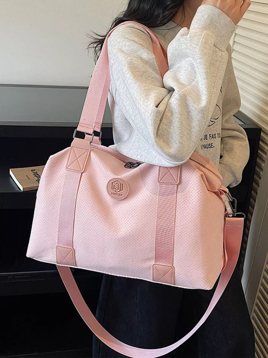 Pink perforated large duffle bag with dual handles and a crossbody strap.