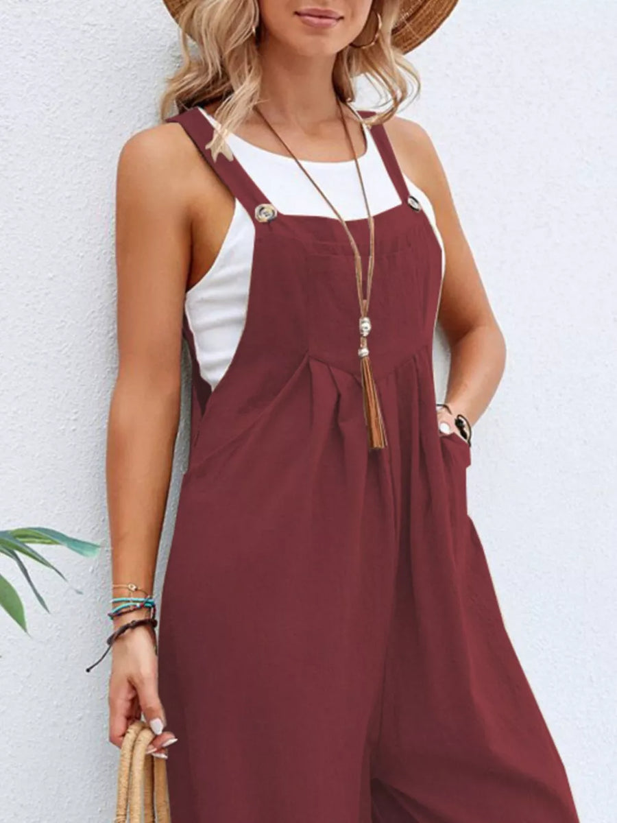 Burgundy wide-leg romper with pockets and button straps, styled with a white tank top.
