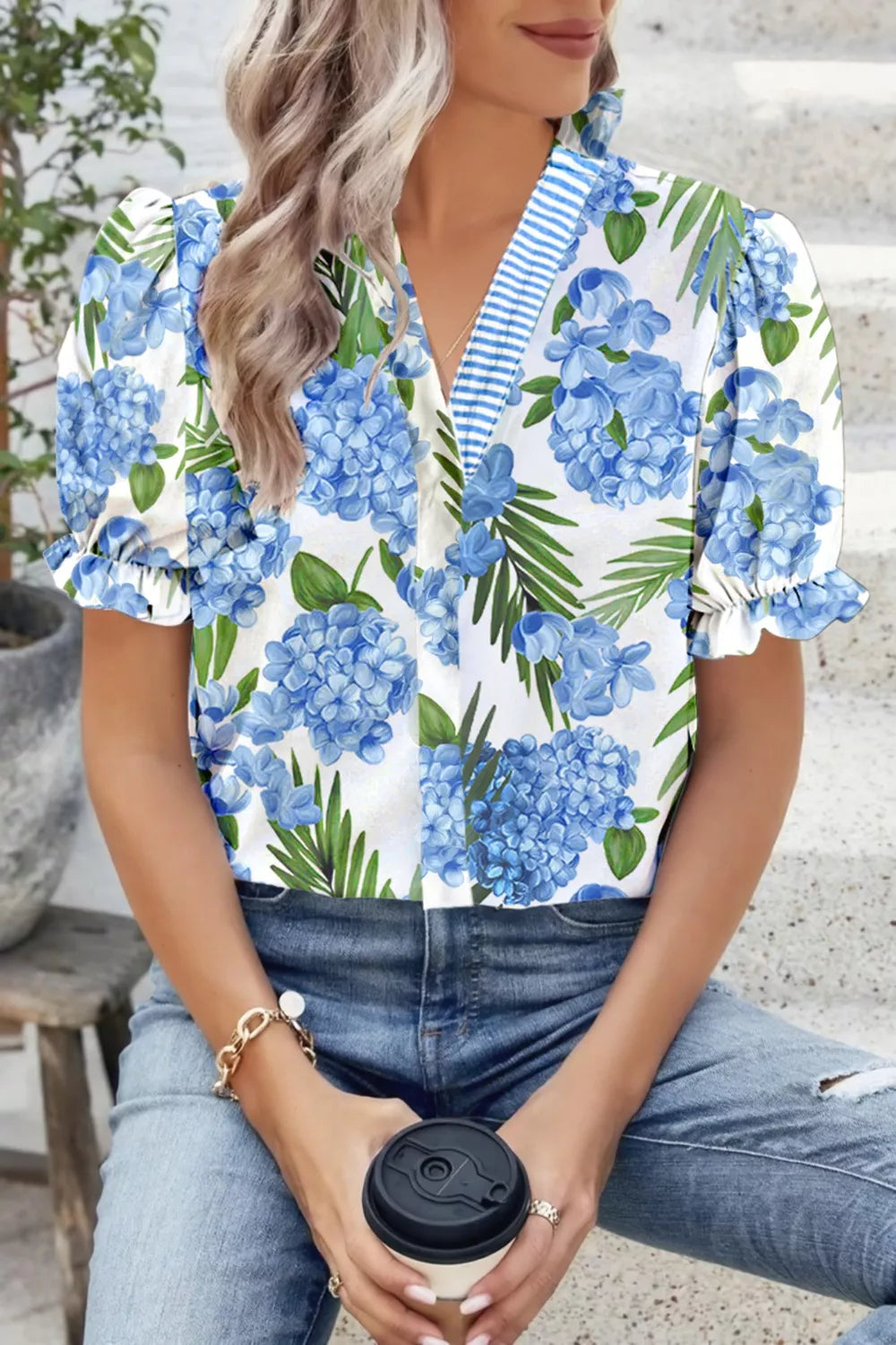 Tropical floral V-neck blouse with blue hydrangea print, puff sleeves, and striped trim.