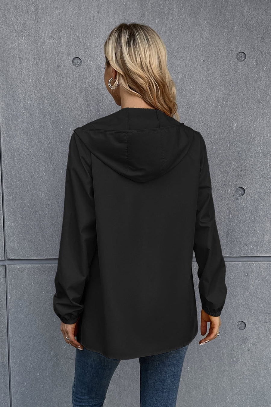 Black hooded rain coat with long sleeves and a relaxed fit.