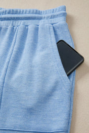 Light blue knit jogger pants with drawstring waist and pocket holding a phone.