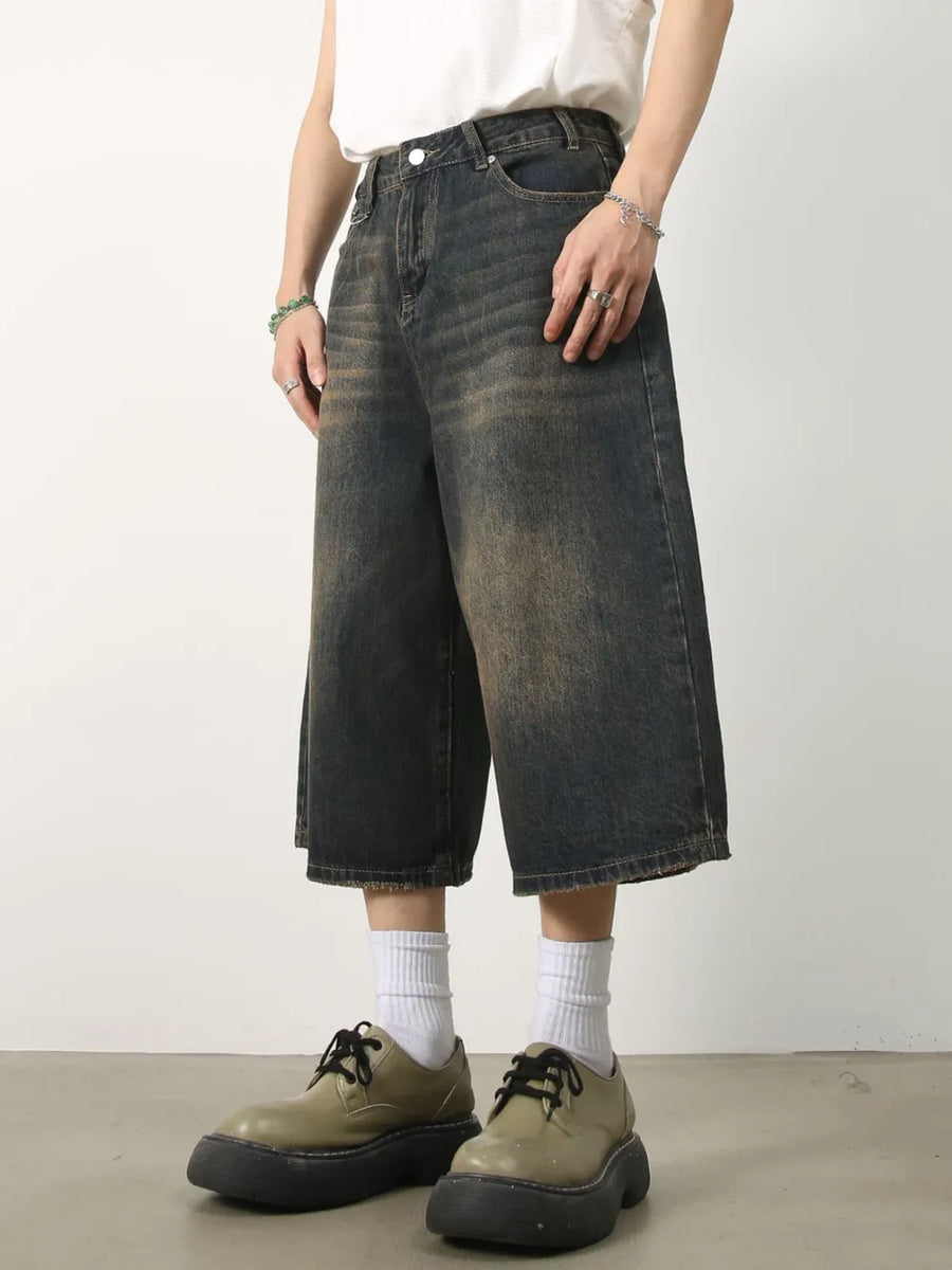 Dark wash denim culottes with distressed details and wide legs.