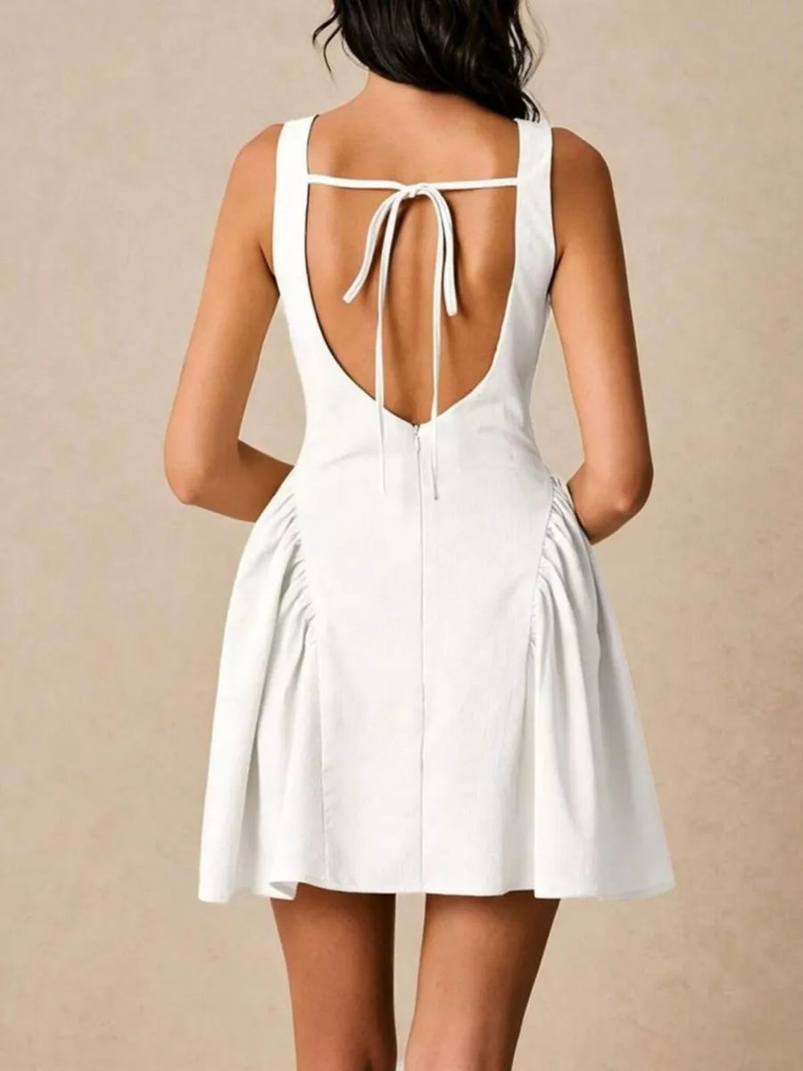 White A-line mini dress with ruched sides and a tie-back detail.