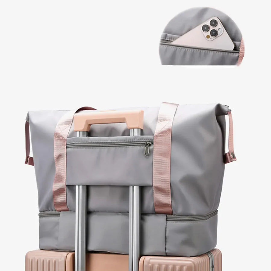 Gray dual-compartment travel tote with metallic trim and exterior phone pocket.