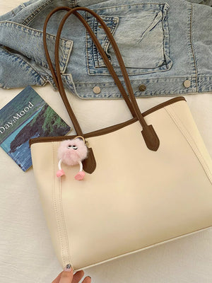 Sophisticated beige PU leather tote bag with brown trim and handles, featuring a fluffy pink charm.