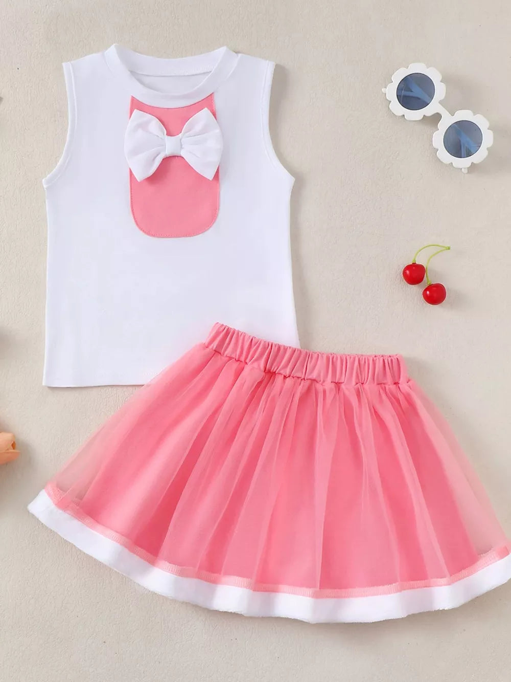 White cotton baby tank top with pink pocket and bow, paired with a pink tulle skirt.