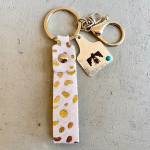 White leather keychain with gold cheetah print and metal charm.