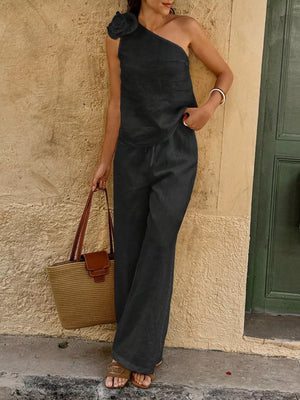 Black cotton one-shoulder top with floral embellishment and wide-leg pants.