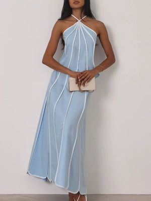 Light blue halter maxi dress with white piping and a cream clutch.
