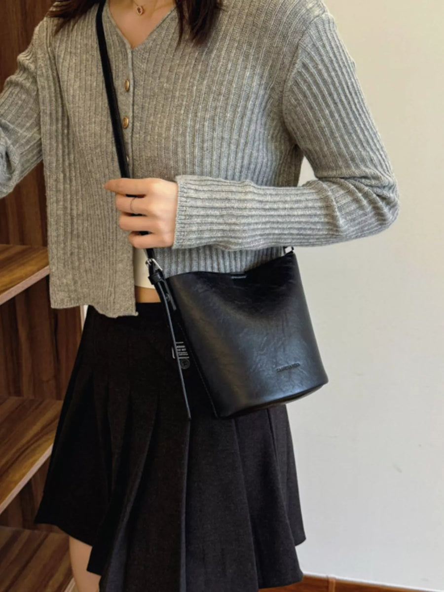 Sleek black leather bucket crossbody bag with adjustable strap.