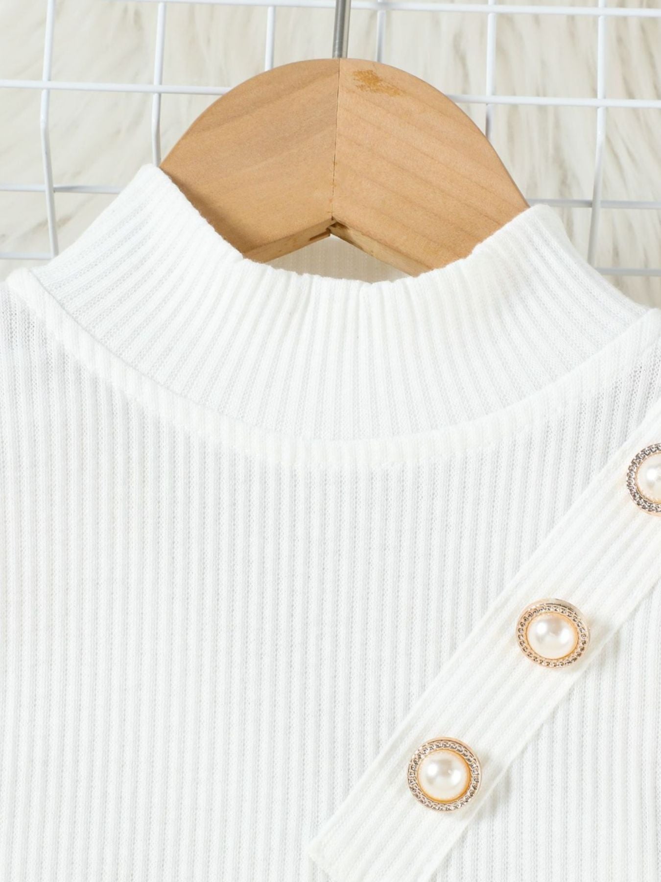 White ribbed mock neck top with pearl and gold button detail