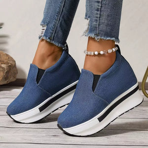 Blue denim slip-on platform shoes with a chunky white sole and black stripe detail.