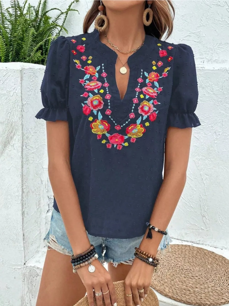 Navy blue embroidered puff sleeve blouse with floral neckline detail and textured fabric.