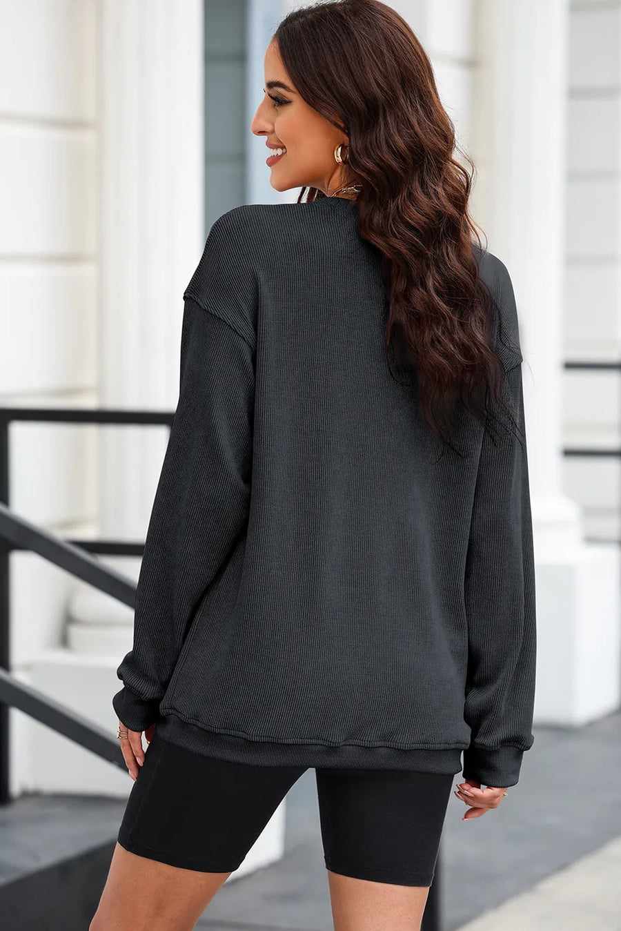 Black ribbed sweatshirt with crew neck and long sleeves, styled with biker shorts.