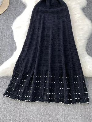 Black knit midi dress with textured pattern and pearl details at hem.