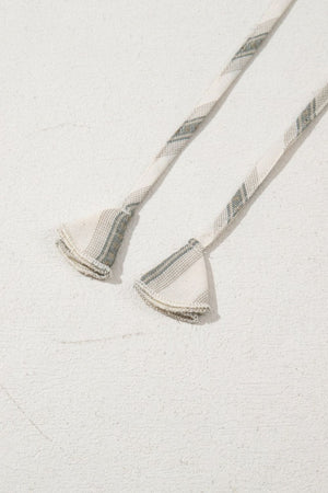 Striped linen blouse detail showing gathered sleeve ends with decorative trim.