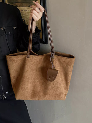 Large caramel brown suede tote bag with leather trim and a circular charm.