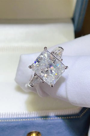 Silver ring with radiant cut moissanite center stone and trapezoid side stones.