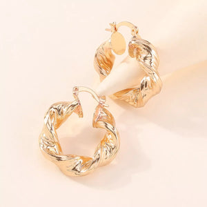 Gold textured hoop earrings with a twisted design.