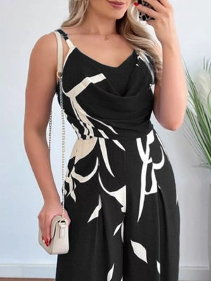 Black abstract leaf print wide-leg jumpsuit with cowl neck and adjustable straps.