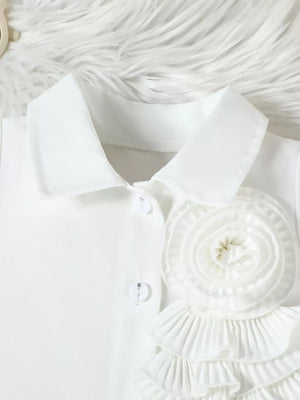 White collared top with decorative fabric flower and ruffled trim.