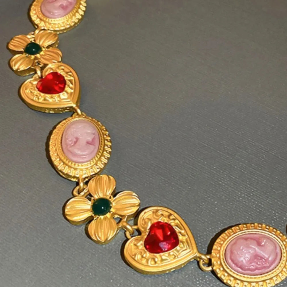 Gold statement necklace with cameo, flower, and heart charms.