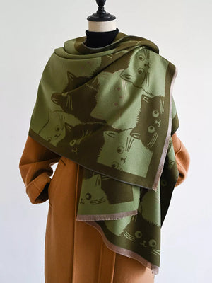Green reversible scarf with a dark brown cat pattern, fringed edges, styled over a tan coat.