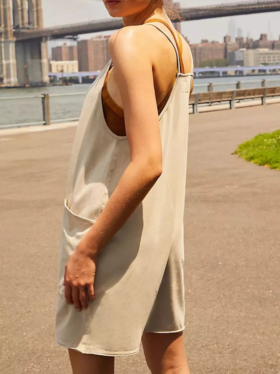 Sleeveless tan linen blend mini dress with pockets and brown straps.