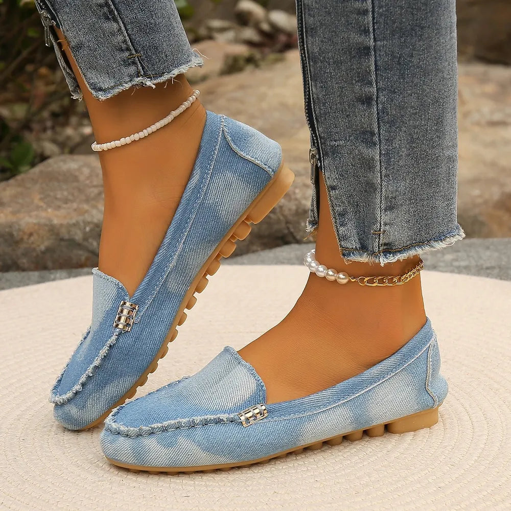 Denim loafers in light wash with frayed edges and silver buckle detail.