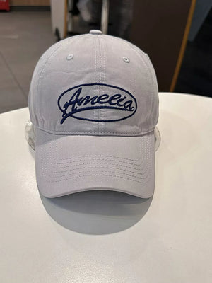 Light grey baseball cap with navy blue embroidered "Amelia" logo.