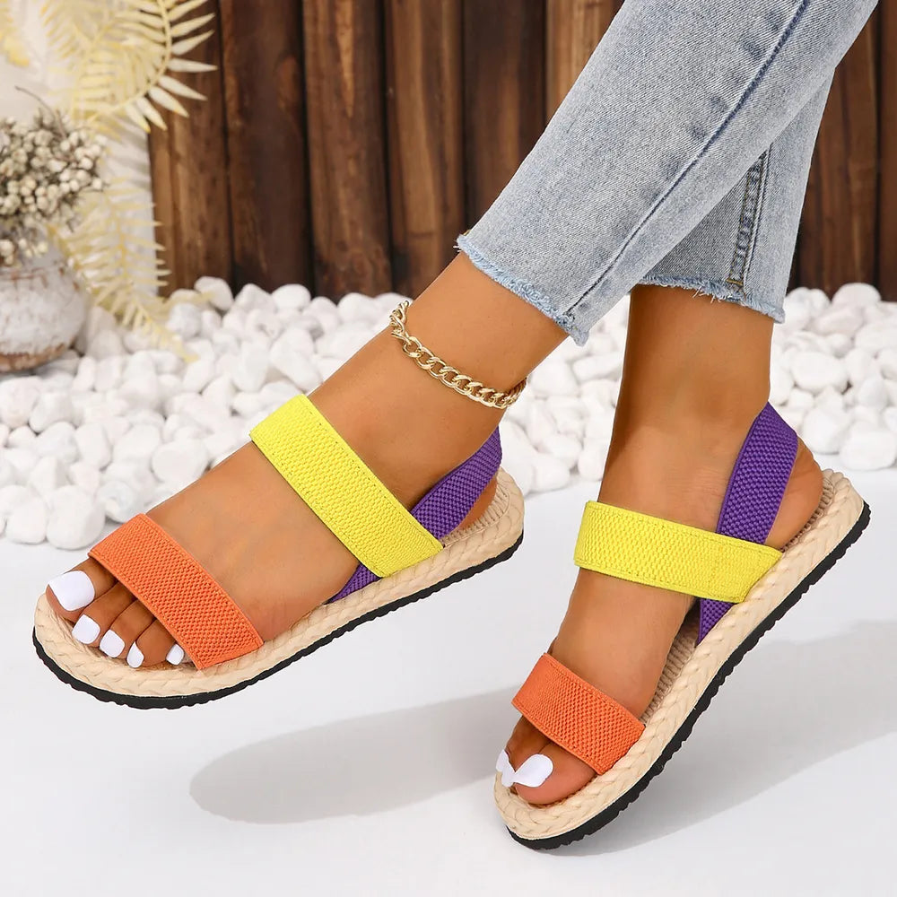 Rope-sole cross-strap sandals in orange, yellow, and purple with adjustable elastic straps.