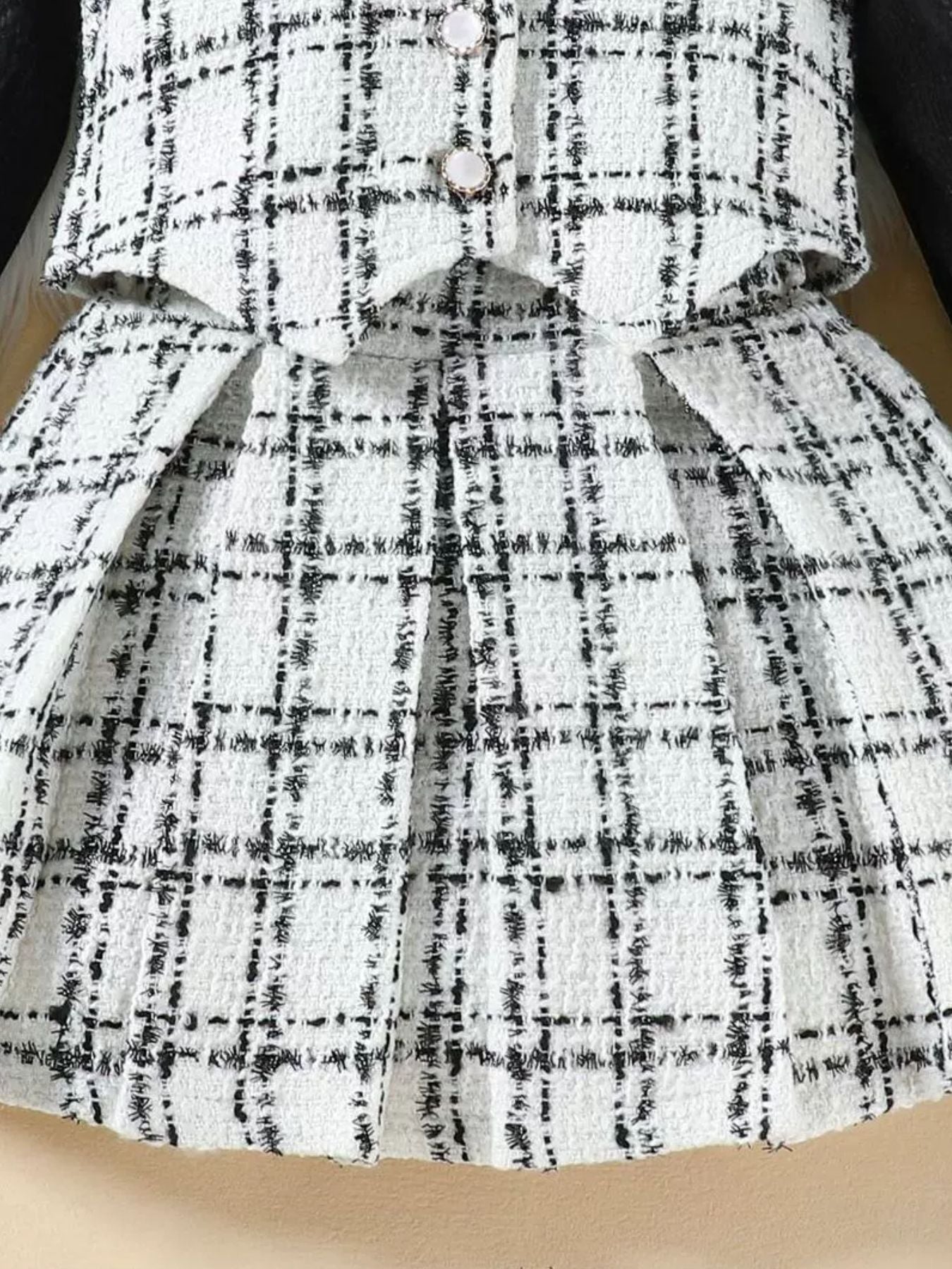 Toddler black and white plaid tweed vest and pleated skirt set with decorative buttons.