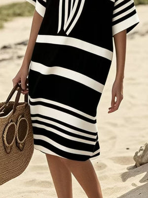 Black and white striped midi dress with half sleeves, worn with a straw bag.