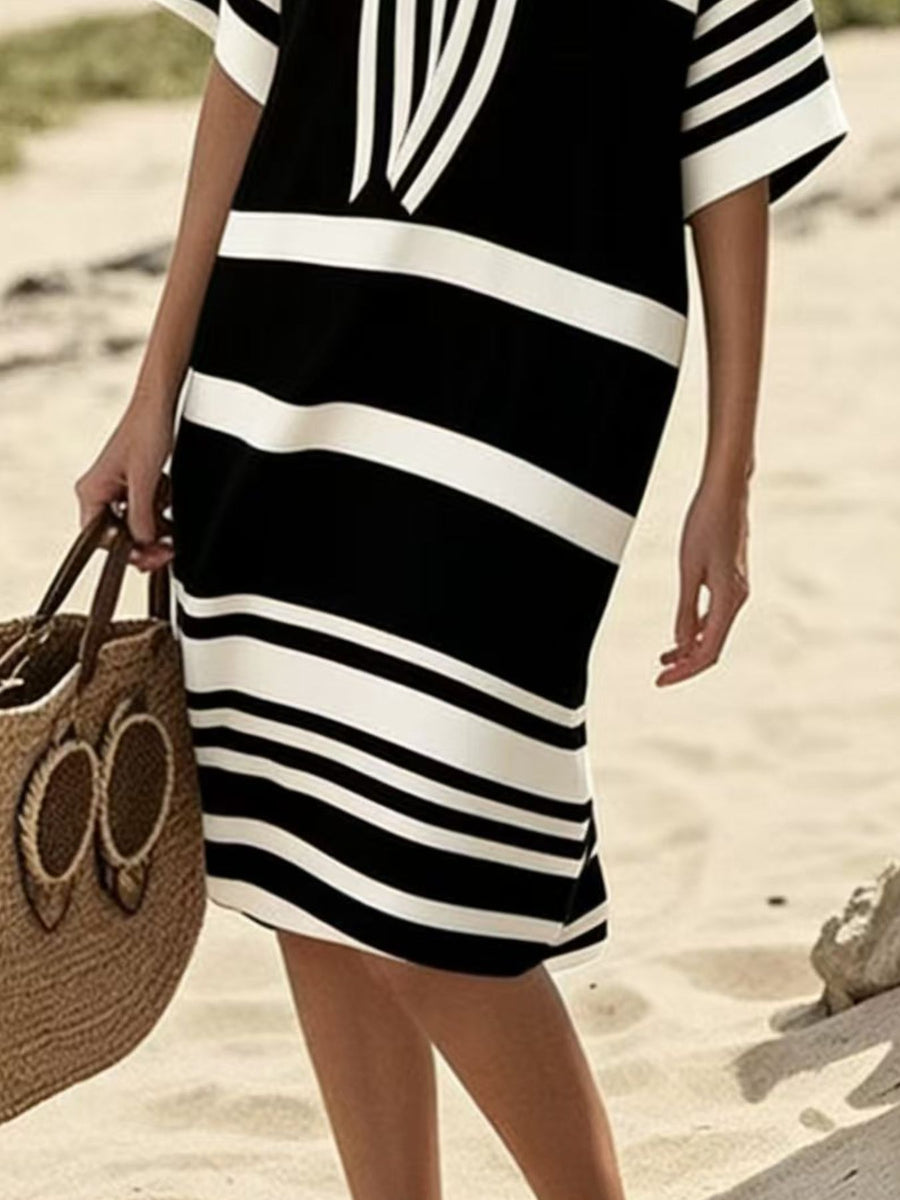 Black and white striped midi dress with half sleeves, worn with a straw bag.