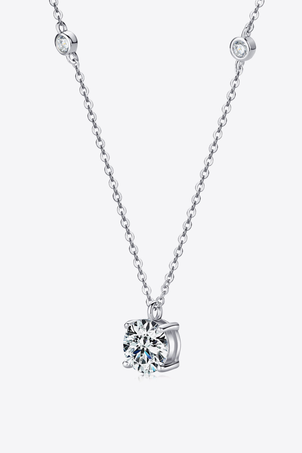 Silver solitaire necklace with a floating moissanite diamond and bezel-set accent stones.