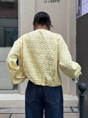 Yellow bomber jacket with textured floral embossed pattern and zip closure.