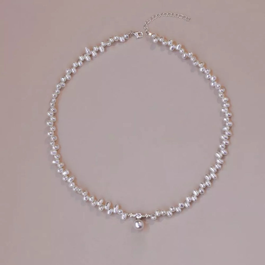 Lustrous irregular pearl pendant necklace with a single pearl drop and crystal accents.