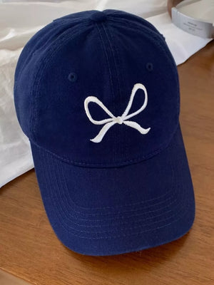 Navy baseball cap with white embroidered bow detail.