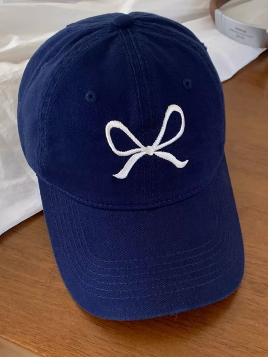 Navy baseball cap with white embroidered bow detail.