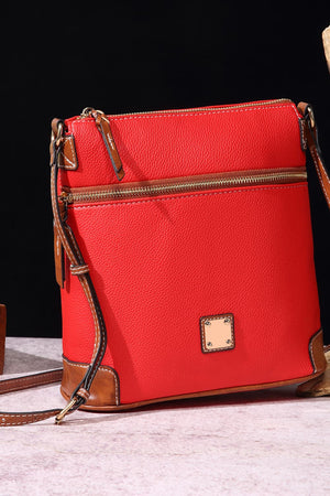 Red leather crossbody bag with brown trim and brass hardware.