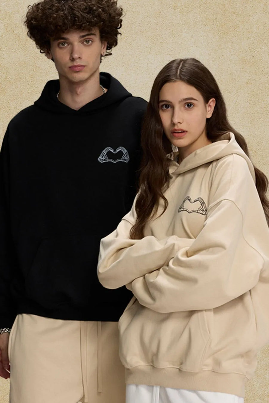 Black and beige oversized hoodies with embroidered heartbeat graphic detail.