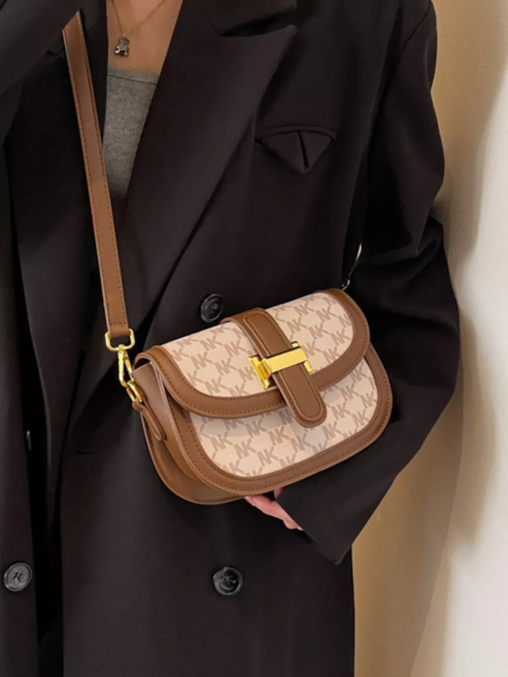 Chic monogrammed flap crossbody bag in tan with brown trim and gold buckle detail.