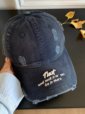 Distressed navy baseball cap with embroidered text and frayed details.