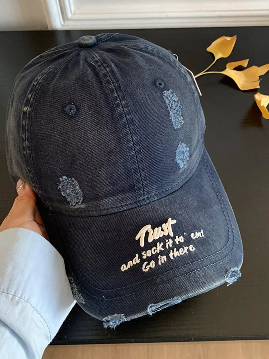 Distressed navy baseball cap with embroidered text and frayed details.