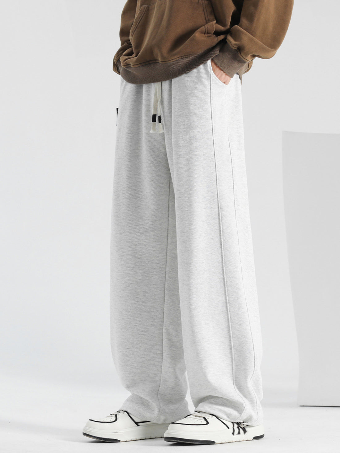 Men's light gray casual drawstring sweatpants with pockets and loose fit.