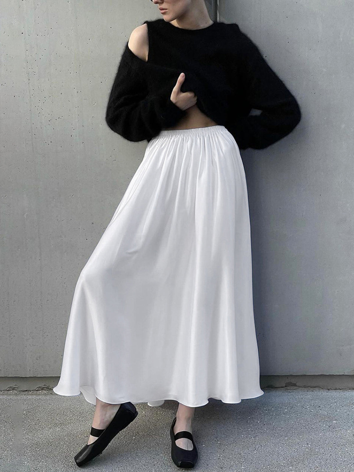 White high-waisted flowy maxi skirt with pockets, styled with a black sweater.