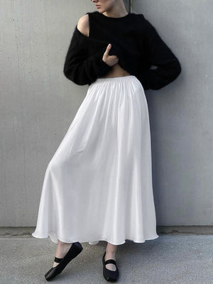 White high-waisted flowy maxi skirt with pockets, styled with a black sweater.