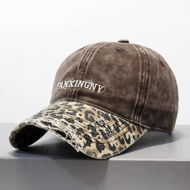 Brown distressed baseball hat with leopard print brim and white text embroidery.
