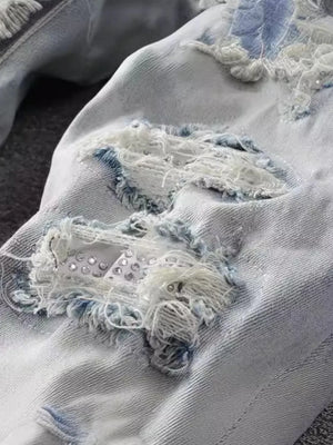 Light wash distressed slim-fit jeans with frayed details and rhinestone embellishments.