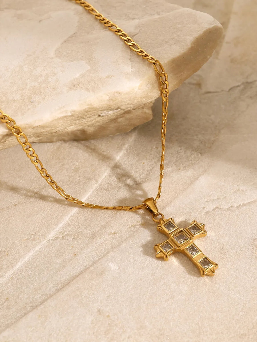 Gold cross pendant necklace with clear zirconia stones on a figaro chain.